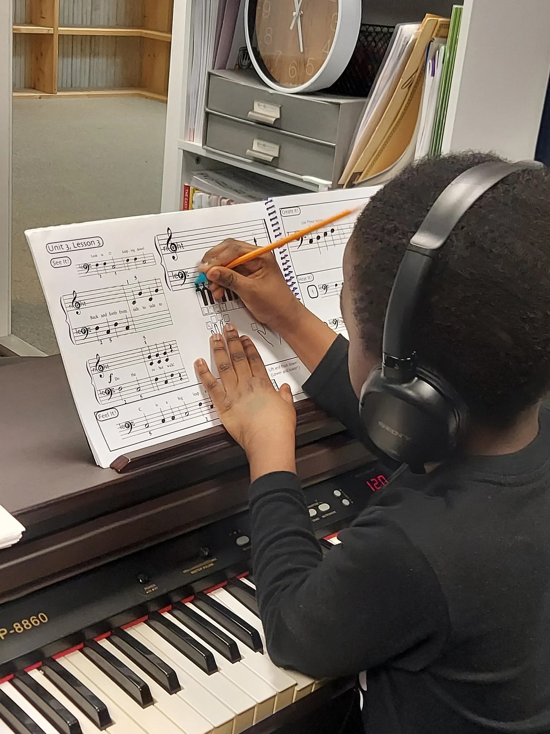 Student writing music notation at piano